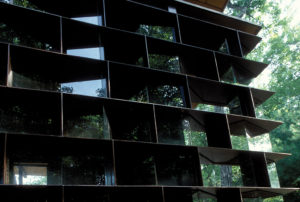 Moore HoneyHouse exterior window looking at steel plate and faceted glass load bearing wall that displays jars of honey