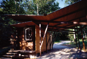 Wooden roof covers the porch and parking spot