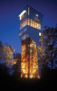 Keenan Tower House lit up at night as it towers over trees in the forest