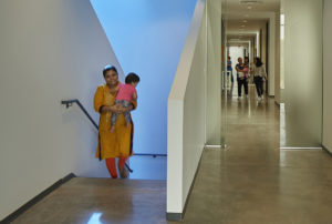 A woman carrying her child up the stairs lit in blue-tinted light