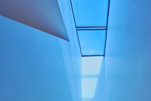 Bright blue light shining down on the stairway from tinted skylight above