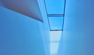 Bright blue light shining down on the stairway from tinted skylight above