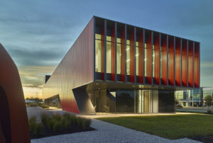 Cayenne color box rib metal cladding wraps the exterior of the clinic at dusk