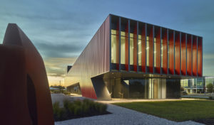 Cayenne color box rib metal cladding wraps the exterior of the clinic at dusk