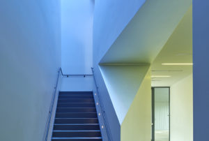 Hallways with high ceilings and white angular walls illuminated in blue light