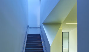 Hallways with high ceilings and white angular walls illuminated in blue light