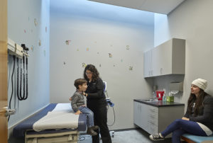 A child receiving a checkup in a doctor's office being lit from above by natural lighting