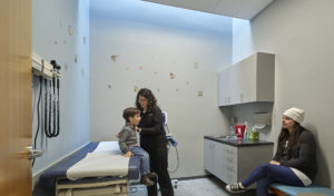 A child receiving a checkup in a doctor's office being lit from above by natural lighting