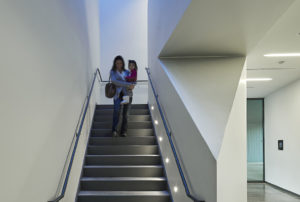 A happy mother and daughter using the white-walled and angled stairway
