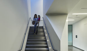 A happy mother and daughter using the white-walled and angled stairway