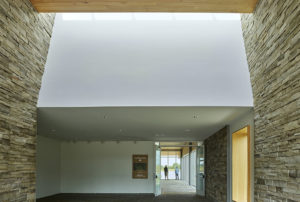 Interior shot of skylight illuminating white a ceiling over rough stone walls