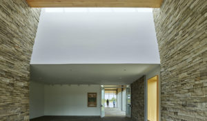 Interior shot of skylight illuminating white a ceiling over rough stone walls
