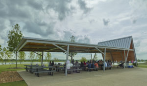 Covered seating in the shade as families eat by the water