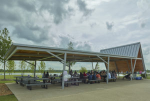 Covered seating in the shade as families eat by the water