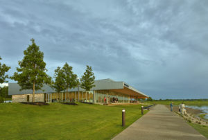 Beautiful view of the building profile seen as patron enjoy the restaurant and storm clouds brew above the structure and landscaping by the lake