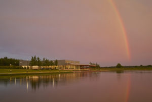 Shelby Farms Park view from across the water at sunset with pink sky and a rainbow
