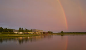 Shelby Farms Park view from across the water at sunset with pink sky and a rainbow