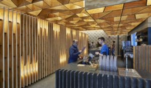 Geometric wooden ceilings and vertical wood slatted walls surround a modern bar with a patron ordering a drink