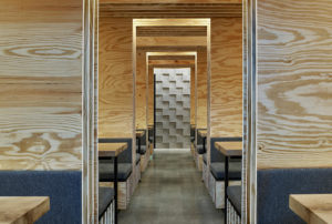 A well-lit hallway with wooden plywood booths on either side