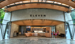 Eleven Servery restaurant wooden checkout bar surrounded by concrete arches and glass walls looking out to water and the Crystal Bridges greenspaces