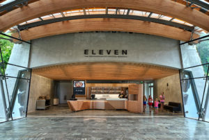 Eleven Servery restaurant wooden checkout bar surrounded by concrete arches and glass walls looking out to water and the Crystal Bridges greenspaces