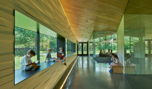 An interior shot of children reading in a window sill of glass, metal, and wood details