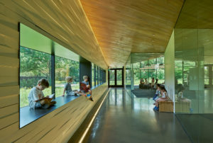 An interior shot of children reading in a window sill of glass, metal, and wood details