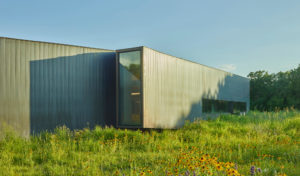 Exterior shot of the metal Innovation Lab building seen through a field of wildflowers