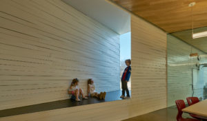 Students in the Innovation Lab leaning against the angular cut walls of the room and sitting in a window sill