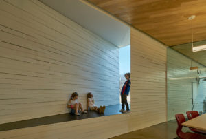 Students in the Innovation Lab leaning against the angular cut walls of the room and sitting in a window sill