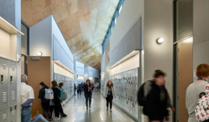 Thaden Reels school hallways featuring bright steel lockers and a steep ceiling above students rushing hurriedly to class