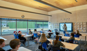Thaden Reels classroom with hanging lights descending from a modern wooden ceiling above a full class of students with their teacher
