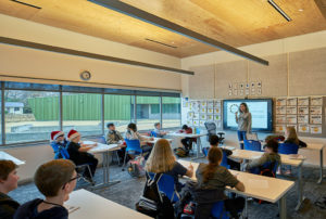 Thaden Reels classroom with hanging lights descending from a modern wooden ceiling above a full class of students with their teacher