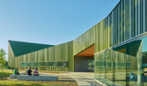 Thaden Reels exterior photo of an angular green building with people sitting on a bench