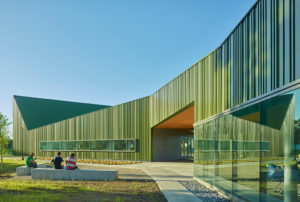 Thaden Reels exterior photo of an angular green building with people sitting on a bench