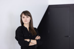 MBA team member headshot featuring a young female architect standing with crossed arms in front of black and white walls