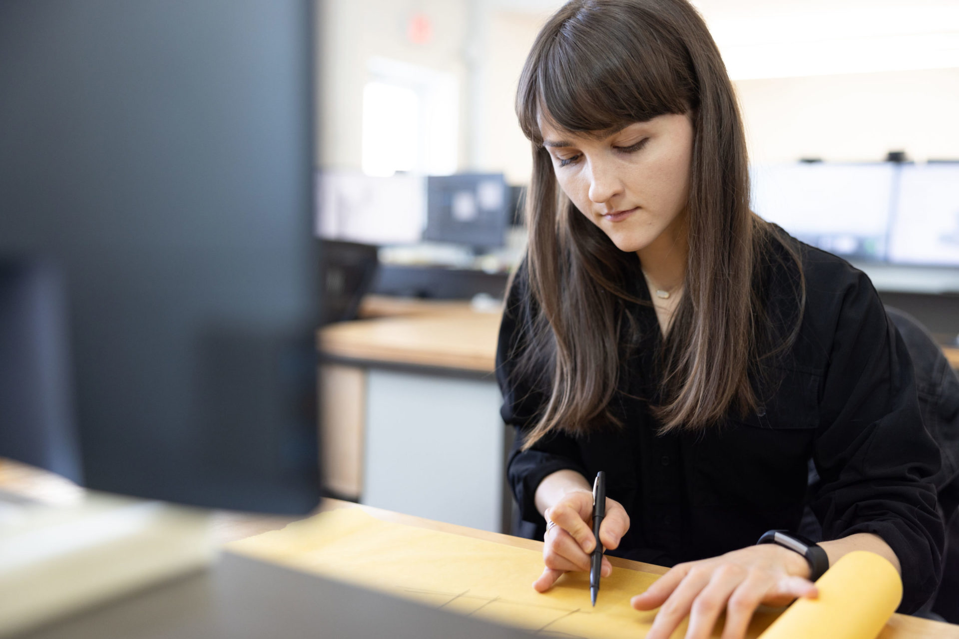 A young female team member with brown hair working on architectural plans with a pen