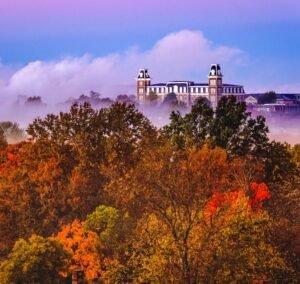 Photograph of University of Arkansas' Old Main over autumn leaves